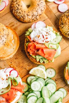 an assortment of bagels and cucumbers on a cutting board