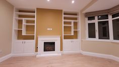 an empty room with built in bookshelves and a fireplace