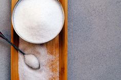 a wooden tray with sugar and spoon on it