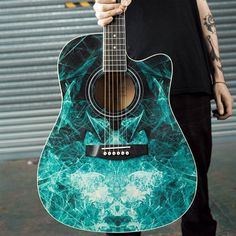 a man holding an acoustic guitar in front of a garage door with graffiti on it