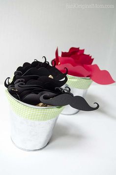 two buckets filled with black and red paper mustaches on top of each other