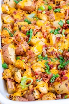 a casserole dish filled with potatoes, bacon and green onions in a white baking dish