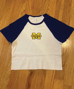 Cropped contrast sleeve baseball tee with Michigan patch White/navy tee Model wearing size XS Size down for a tight fit Blue Baseball Collar Top For Game Day, Blue Varsity Top With Baseball Collar, Casual Raglan Sleeve T-shirt For College, Navy Collegiate T-shirt For College, Navy Collegiate Style T-shirt For College, Collegiate Style Navy T-shirt For College, Sporty College T-shirt With Baseball Collar, Blue Cotton Tops With Baseball Collar, Navy Tops With Letter Print For Baseball Season