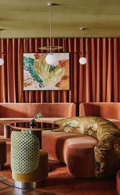 a living room filled with lots of furniture next to a window covered in orange drapes