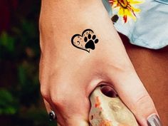 a woman's hand with a small paw tattoo on it