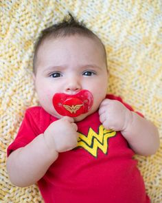 a baby with a pacifier in it's mouth laying on a yellow blanket