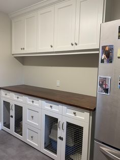 a kitchen with white cabinets and dog kennels on the counter top, in front of a stainless steel refrigerator