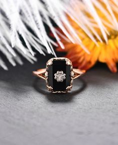 a black and white diamond ring sitting on top of a table next to some flowers