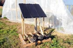 there is a small solar panel on top of a wooden stand in the grass next to a fence