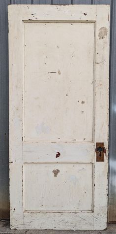 an old white door with a rusted lock on the bottom half and side panel