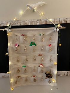 a white wall hanging with lots of earrings on it's sides and lights in the middle