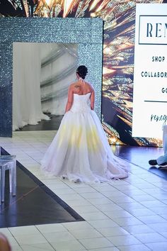 a woman in a white dress walking down a runway