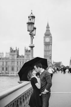 a couple kissing under an umbrella in front of the big ben clock tower, london