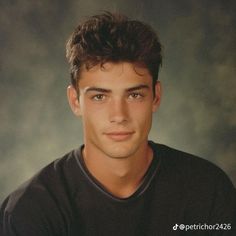 a young man in a black shirt is looking at the camera with an intense look on his face