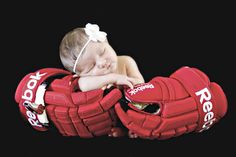 a baby sleeping on top of two hockey gloves