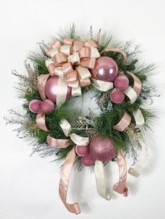 a pink and white christmas wreath hanging on the wall