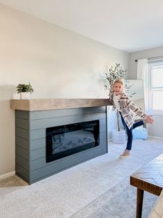 a girl is jumping in the air near a fireplace