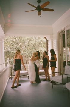 four women in bathing suits are standing on the porch with their arms around each other