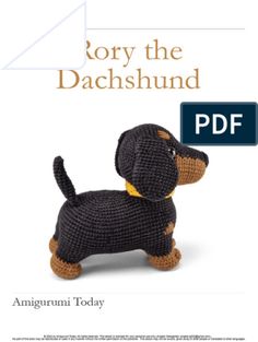 a crocheted black and brown dog sitting on top of a white book cover