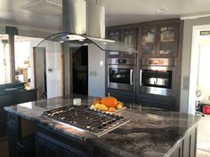 a kitchen with marble counter tops and stainless steel ovens in the center, surrounded by wooden cabinets