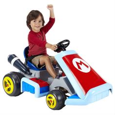 a young boy is riding on a toy car with wheels and steering wheel in the shape of a mario kart