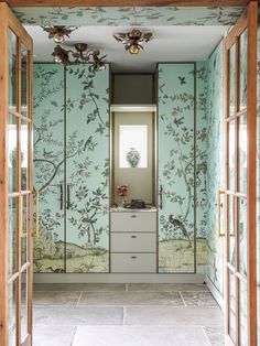 an open door leading into a room with wallpaper and flowers on the walls,