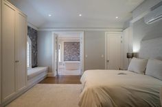 a large white bed sitting in a bedroom next to a window