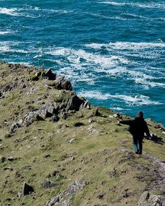 a person standing on top of a cliff near the ocean