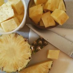 sliced pineapples and other fruits on a cutting board next to a large knife