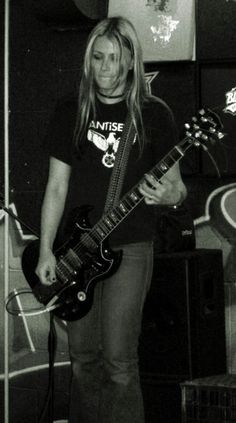 a woman standing in front of a microphone holding a guitar