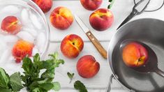 fresh peaches and ice in bowls on a white table with utensils next to them