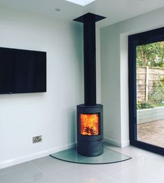 a room with a television and a fire place in the corner that has glass doors on both sides