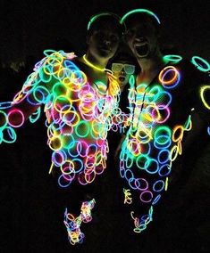 two men standing next to each other with colorful lights on their bodies and hands in front of them