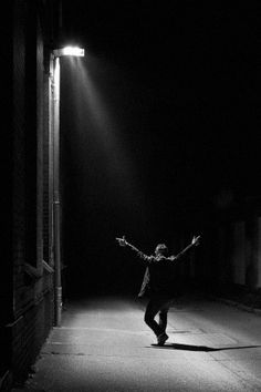 a person standing in the dark with their arms outstretched