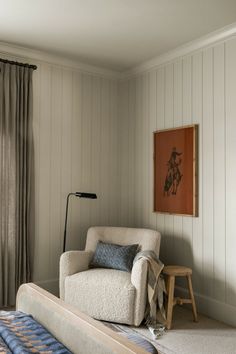 a living room with a chair, lamp and rug in front of a painting on the wall