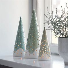 three small christmas trees sitting on top of a white shelf next to a window sill