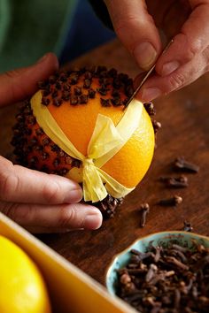 a person cutting an orange on top of a wooden table