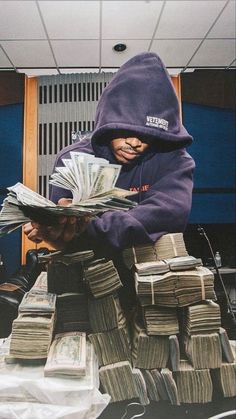 a man in a purple hoodie is holding stacks of money