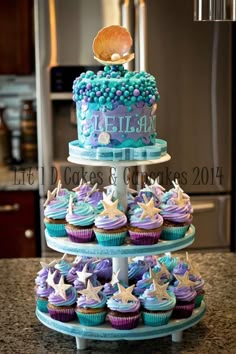 three tiered cake with cupcakes on top