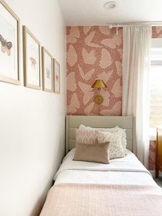 a bedroom with pink wallpaper and white bedding