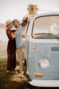 a man and woman standing next to an old vw van