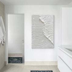 a white bathroom with an abstract painting on the wall