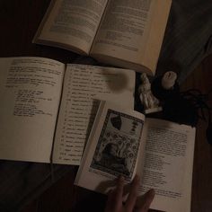 an open book sitting on top of a wooden table next to a candle and some books