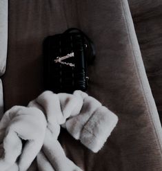 a white fur coat laying on top of a couch next to a black purse and remote control