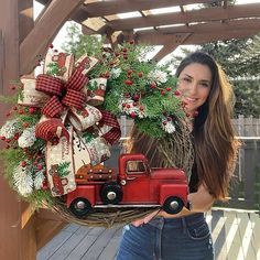 a woman holding a christmas wreath with a red truck