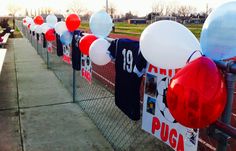 balloons and t - shirts are hanging on the fence