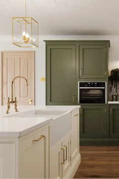 a large kitchen with green cabinets and white counter tops, gold pulls on the handles