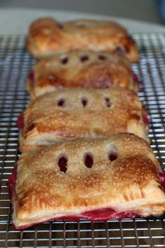 four pastries sitting on top of a cooling rack with cherries in the middle