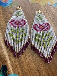 two pairs of beaded earrings sitting on top of a wooden table