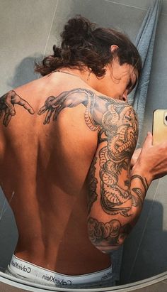 a man with tattoos on his back taking a selfie